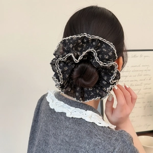 Floral black scrunchie with white lace trim shown on a bun in a lifestyle setting