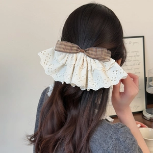 Pince à cheveux élégante avec nœud à carreaux marron et dentelle sur un mannequin femme