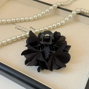 Dettaglio del fermaglio per capelli a fiore in chiffon nero su vassoio con perle