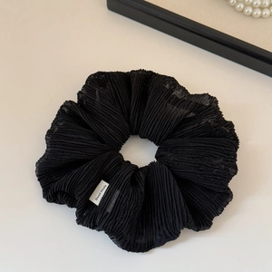 Close-up of black mesh pleated scrunchie with a handmade label and elegant pearl details