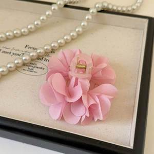 Dettaglio di un fermaglio per capelli in chiffon rosa con molla dorata in portagioie