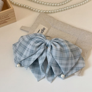 Détail d'une pince à cheveux à nœud écossais bleu clair avec des pendentifs en perles
