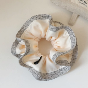 Close-up of dual-tone ruffled scrunchie featuring beige satin and grey textured trim fabric
