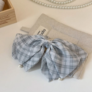 Gros plan d'une barrette à nœud écossais gris avec d'élégants pendentifs en perles