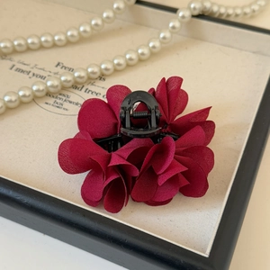 Dettaglio macro della molletta per capelli a fiore in chiffon bordeaux con perle