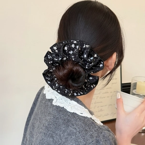 Elastico scrunchie nero floreale su capelli a coda bassa in un contesto elegante