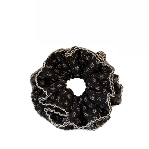 Chic black floral scrunchie with white lace edges and a ruffled layered design