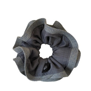 Double-layered pleated scrunchie in dark grey with linen texture and logo tag
