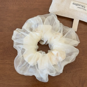 Détail du chouchou géant en organza crème avec des plis soyeux et une texture fine