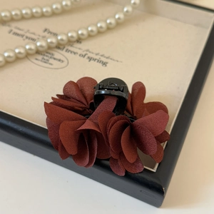 Dettaglio del fermaglio per capelli a fiore in chiffon bordeaux con petali a più strati