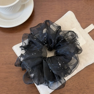 Détail d'un chouchou noir en mesh double couche avec des paillettes argentées brillantes