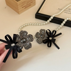 Detail of floral rhinestone hair clip with white pearls and a black ribbon bow accessory
