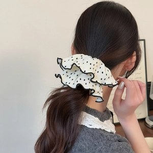Nahaufnahme eines plissierten Polka-Dot-Haargummis mit schwarzer Rüschenkante am Zopf