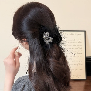 Elegant black feather hair claw clip with rhinestone butterfly on long brown hair