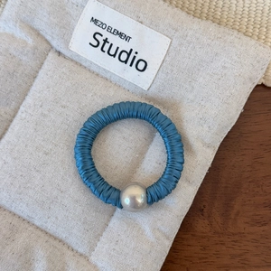 Détail d'un chouchou élégant en satin de soie bleu foncé avec une grande perle décorative