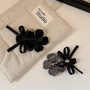 Close-up of black flower hair clip with sparkling rhinestones and satin ribbon bow