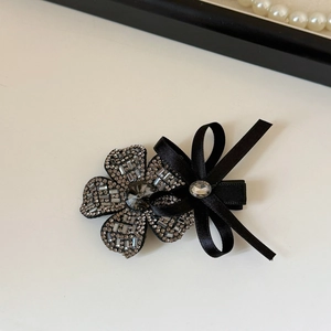 Detail shot of elegant floral hair clip with grey rhinestones and black satin ribbon bow