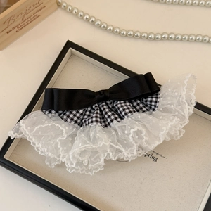 Détail du tissu pied-de-poule et dentelle à pois sur une barrette à nœud rétro chic