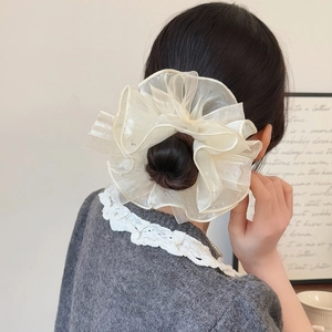 Chouchou élégant en organza blanc crème avec strass scintillants porté sur un chignon