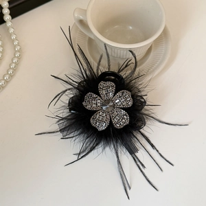 Detailed close-up of crystal flower and black feathers on an elegant hair claw clip
