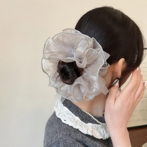 Détail d'un chouchou en organza gris avec strass sur les cheveux montrant la texture