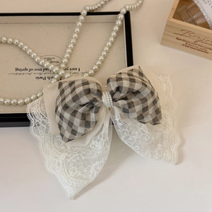 Detail of grey plaid and beige lace bow hair claw clip with triple row pearl accents