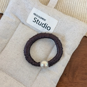 Détail de l'élastique à cheveux en satin marron foncé avec une perle décorative argentée