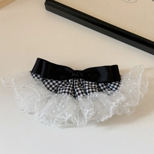Détail d'une barrette en dentelle pied-de-poule avec nœud en satin noir élégant
