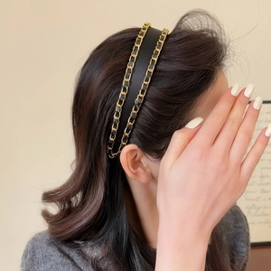 Close-up of elegant black leather headband with double golden chain weaving design