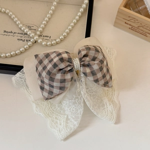 Detail view of the lace embroidery and pearl beads on the brown plaid bow hair clip
