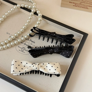 Tre fermagli per capelli vintage con fiocco a pois bianchi e neri su un espositore