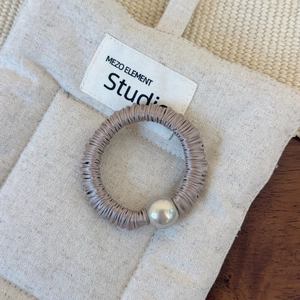 Détail d'un chouchou en soie marron grisâtre avec une perle argentée métallique