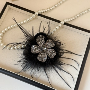 Detail of luxury black flower hair claw with shimmering diamonds and soft feathers