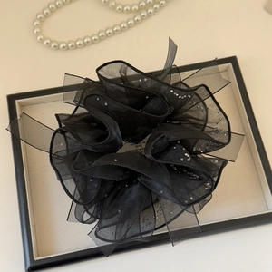Détail d'un chouchou élégant en organza noir orné de strass brillants sur un support