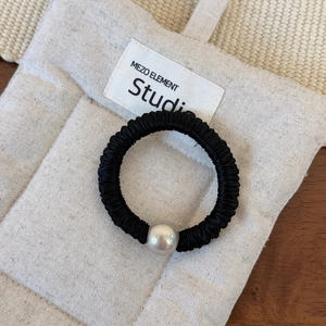 Détail d'un chouchou en satin plissé noir orné d'une grande perle décorative unique