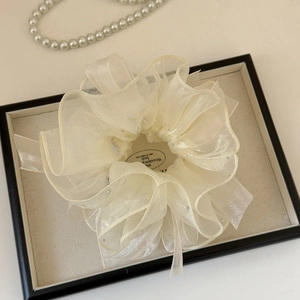 Détail d'un chouchou en organza crème avec strass dans un coffret à bijoux chic