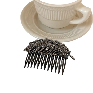 Elegant black leaf hair comb featuring dark rhinestones on a white background with decor