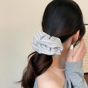 Striped scrunchie hair tie in grey and white worn by a model in a minimalist low ponytail