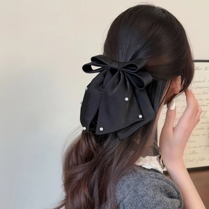 Elegant black satin bow hair clip with white pearls on model for sophisticated hairstyling