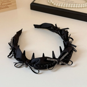 Dettaglio di cerchietto in raso nero con fiocco di strass e denti interni antiscivolo