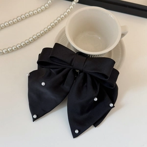 Detail of elegant black satin bow hair clip with small white pearl accents