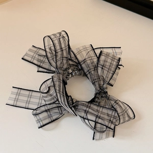 Detail of checkered bow hair scrunchie with sparkling rhinestone center and ribbon texture