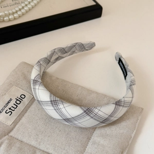 Detail of plaid headband with handmade label on beige quilted fabric background