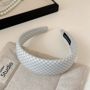 Detailed view of a light blue checkered headband with handmade label on linen fabric