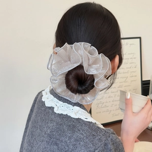 Chouchou en organza gris clair avec paillettes porté sur un chignon élégant