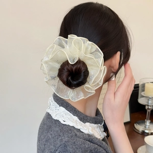 Gros plan d'un chouchou en organza crème avec strass sur une coiffure en chignon