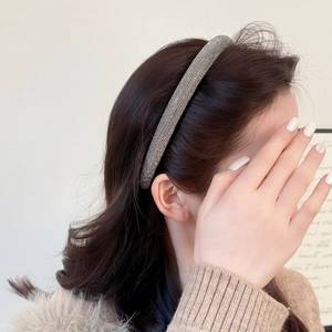 Elegant thin headband with shimmering white crystals and dark metallic base on a model