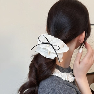 Chouchou élégant en mousseline blanche avec nœud noir et perle sur une coiffure basse
