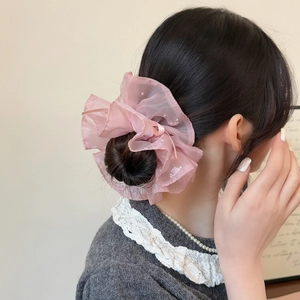 Chouchou en tulle rose avec perles et ruban porté sur un chignon élégant