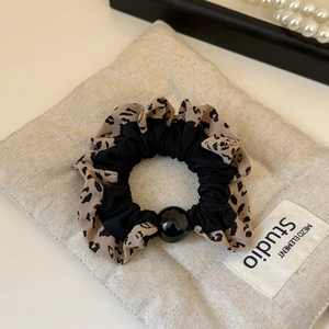 Detailed close-up of leopard print and black fabric scrunchie with a glossy bead